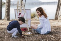 Mother and boy painting near lake — Stock Photo