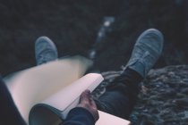 Vista para o pequeno rio em cânion e pernas de pessoa com livro sentado na borda — Fotografia de Stock