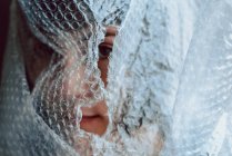 Woman looking at the camera while entangled in bubble wrap — Stock Photo