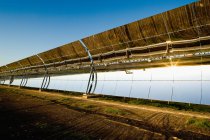 Oberfläche moderner Sonnenkollektoren reflektiert helle Sonne auf Photovoltaik-Kraftwerk gegen wolkenlosen blauen Himmel — Stockfoto
