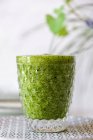 Healthy green smoothie of spinach, avocado and kiwi, apple and lemon in glass on plate — Stock Photo