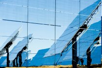 Відбиття сучасних сонячних панелей на скляній стіні під час сонячного дня в фотоелектричній електростанції в сільській місцевості — стокове фото