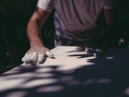 Руки анонимного художника-мужчины, распространяющего грубую белую штукатурку на ровную поверхность в мастерской — стоковое фото