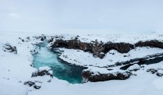 Вид потужного потоку води і скелі покриті снігом, водоспад Годафосс, Ісландія — стокове фото