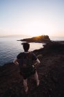 Männlicher Wanderer beobachtet Sonnenuntergang über abgelegener Küste — Stockfoto