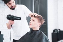 Peluquería secar el cabello a la mujer - foto de stock