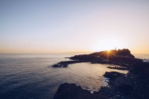 Bord de mer rocheux éloigné au coucher du soleil lumineux — Photo de stock
