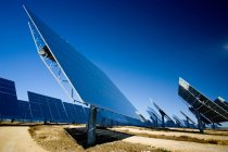 Painéis solares modernos instalados no campo contra o céu azul sem nuvens na central fotovoltaica — Fotografia de Stock