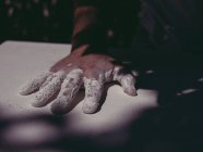 Hand of anonymous male artist spreading rough white plaster on plain surface in workshop — Stock Photo