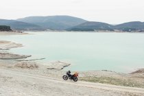 Moto parcheggiata sulla strada di campagna sulla riva del tranquillo lago durante il viaggio nella natura — Foto stock