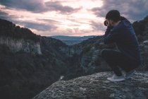 Hombre con cámara de fotos sentado en la montaña de la colina con magnífica puesta de sol - foto de stock
