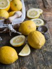 Limones frescos y exprimidor de madera sobre tabla de madera - foto de stock