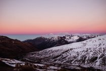 Klarer Himmel bei Sonnenuntergang über wunderschönen, mit weißem Schnee bedeckten Bergen — Stockfoto