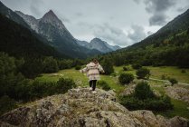 Visão traseira da mulher irreconhecível em roupa casual correndo no topo da colina rochosa áspera no dia nublado no majestoso vale — Fotografia de Stock