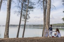 Madre e ragazzo pittura vicino lago — Foto stock