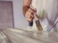 Unrecognizable male artist with paintbrush covering rough canvas with paint in workshop — Stock Photo