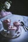 Copos de mousse de morango doce na mesa com flores — Fotografia de Stock