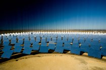 Сучасні сонячні панелі, що відображають яскраві промені на фоні безхмарного блакитного неба в сонячний день на фотоелектричній електростанції — стокове фото