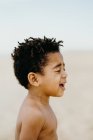Seitenansicht von entzückenden hemdlosen afrikanischen amerikanischen Jungen mit geschlossenen Augen, während er auf verschwommenem Hintergrund des Strandes steht — Stockfoto