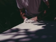 Mãos de artista masculino anônimo espalhando gesso branco áspero na superfície lisa na oficina — Fotografia de Stock