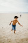 Смешной афроамериканец играет на песчаном берегу у моря — стоковое фото