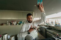 Camarero vertiendo bebida alcohólica en vidrio en el bar - foto de stock