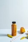 Манго и тыквенный веганский смузи в бутылке на белом фоне с ингредиентами — стоковое фото