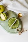Healthy green smoothie of spinach, avocado and kiwi, apple and lemon in glass on wooden board with ingredients — Stock Photo