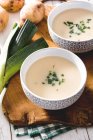 Стреляйте сверху из двух тарелок вкусных супов Vichyssoise на деревянном столе с луком-порей — стоковое фото