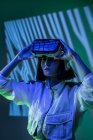 Excited young woman wearing virtual reality goggles in neon light — Stock Photo