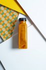 Манго и бутылка смузи из-под тыквы поверх геометрической текстуры в стиле ретро — стоковое фото