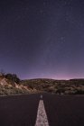 Estrada vazia à noite sob estrelas brilhantes — Fotografia de Stock
