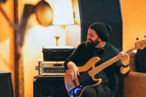 Erwachsener Mann sitzt im Musikstudio und spielt Gitarre — Stockfoto