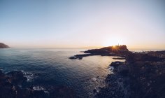 Bord de mer rocheux éloigné au coucher du soleil lumineux — Photo de stock