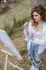 Jovem mulher pintura no campo — Fotografia de Stock