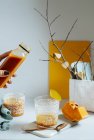 Mano femminile che serve frullato di mango fresco in bicchieri sul tavolo bianco — Foto stock