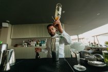 Barman pouring alcoholic drink to shaker in bar — Stock Photo