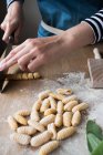 Anonymous female cutting dough for homemade gnocchetti pasta on table in kitchen — Stock Photo