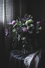 Ramo de flores sobre una mesa en habitación oscura vintage - foto de stock