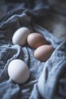 Chicken eggs on tablecloth on rustic wooden table — Stock Photo