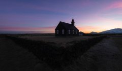 Paisaje de montaña con iglesia cristiana de madera negra Budakirkja en Islandia - foto de stock