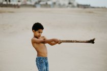 Смешной афроамериканец с палкой играет на песчаном берегу у моря — стоковое фото