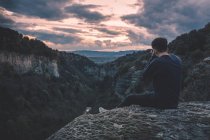 Homem com câmera de foto sentado na montanha colina com pôr do sol magnífico — Fotografia de Stock