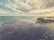 Costa rocciosa e mare azzurro sullo sfondo del cielo con nuvole — Foto stock