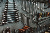 Set verschiedener Reparaturwerkzeuge, die in der professionellen Werkstatt an einer gröbsten Metallwand befestigt werden — Stockfoto