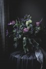 Bouquet of flowers on a table in dark vintage room — Stock Photo