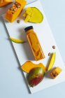 Манго і гарбузова веганська смузі в пляшці на білій дошці з інгредієнтами — стокове фото