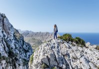 Young woman standing on cliff — Stock Photo