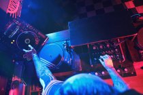 Крупный план анонимного диджея, играющего в клубе со светом — стоковое фото