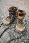 Paire de bottes de randonnée altérées placées sur une route pierreuse à la campagne — Photo de stock